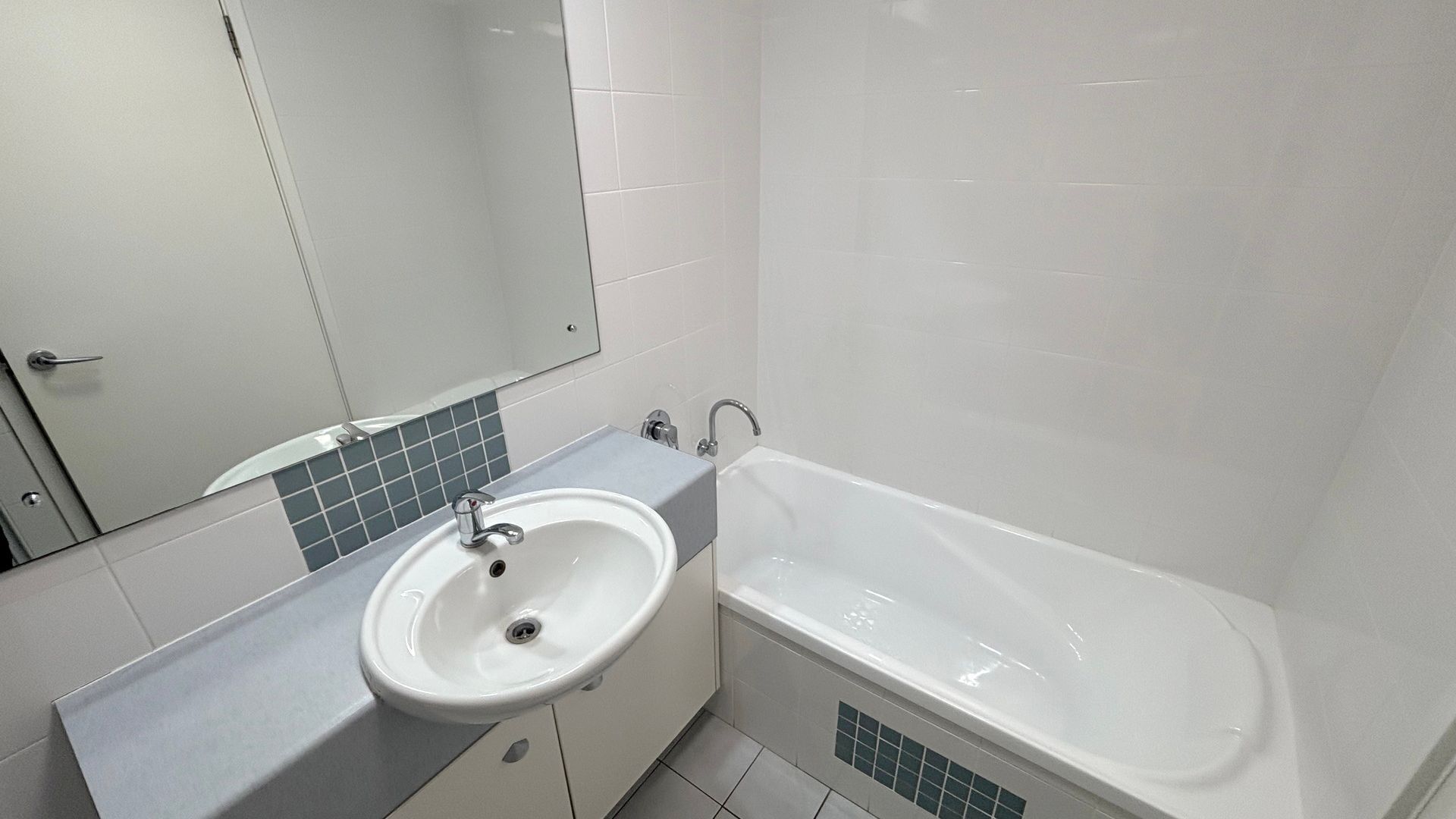 A bathroom with a sink, mirror, and bathtub.