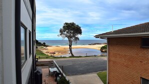 A view of a beach from a building with a brick exterior and a window overlooking the ocean. - Waterford Apartment 4 (SOUTH WEST ROCKS)