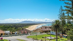 A coastal property with a beach view, a fenced area, and a small building with a sign. - Astor Apartment 2 - walk to the beach (SOUTH WEST ROCKS)