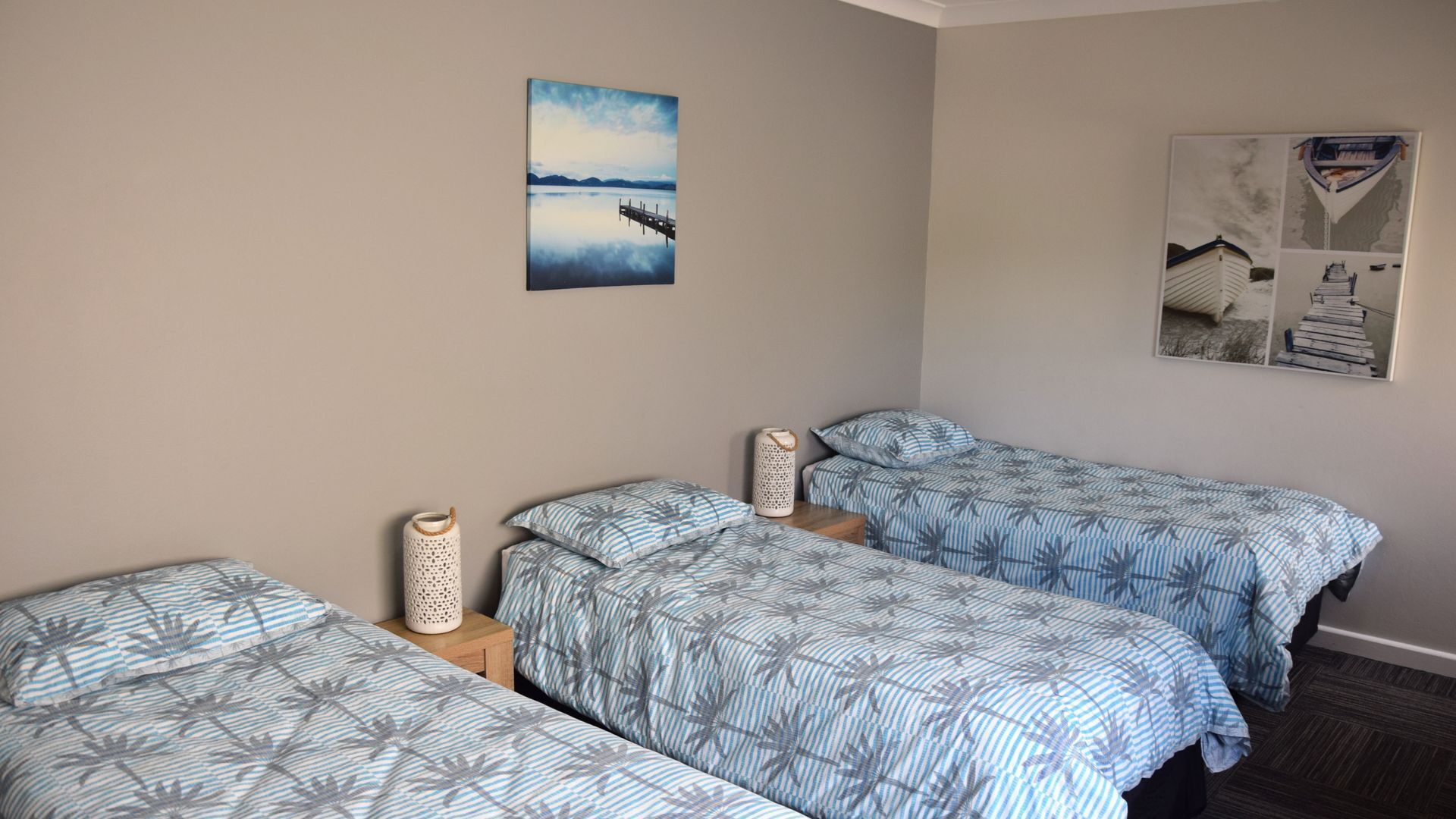 Una habitación con dos camas individuales, una mesita y un estante en la pared.