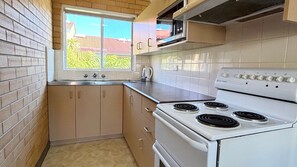 Una cocina con estufa blanca, una ventana y vistas a edificios.