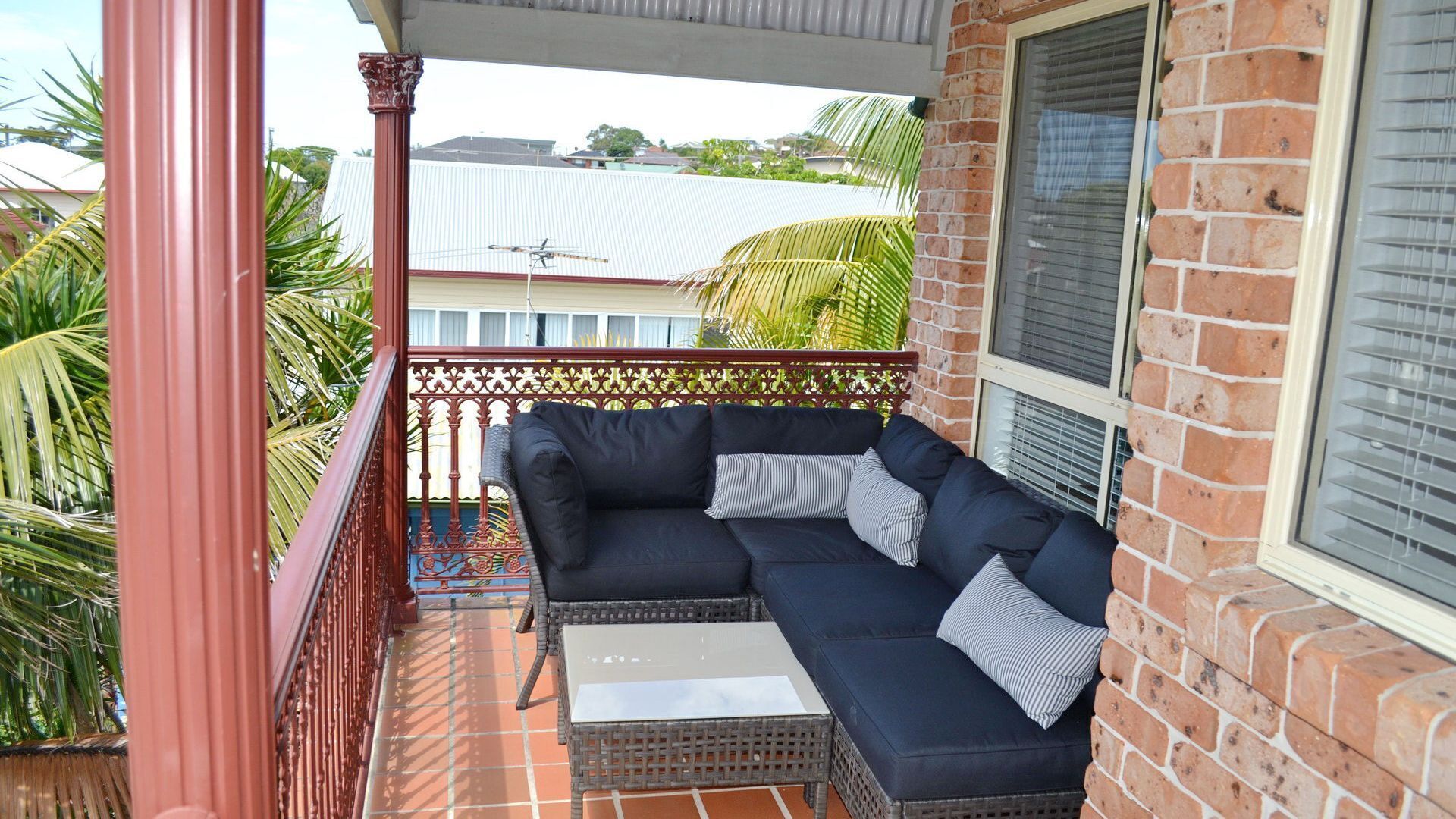 A balcony with a dark blue sofa, two cushions, and a small table.