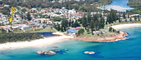 A coastal town with a beach, houses, and a bridge.