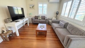Una sala de estar con televisor, dos sofás, una mesa de centro y una lámpara.