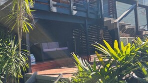 Un espace extérieur moderne, aménagé avec une terrasse en bois et entouré de plantes tropicales.