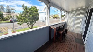 A covered porch with a view of a street and a tree. - Captains Cottage SWR (SOUTH WEST ROCKS)