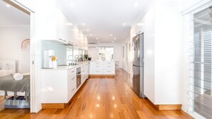 A modern kitchen with white cabinetry, a built-in oven, and a refrigerator.