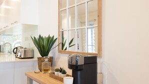A modern kitchen with a coffee machine, a kettle, and a plant on the counter.