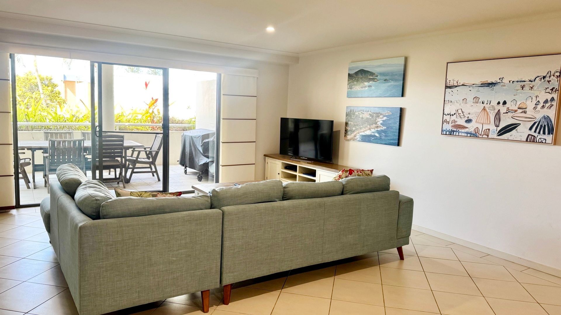 A living room with a sofa, a TV, and artwork on the wall.