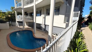 A residential building with a swimming pool, balconies, and a fenced area. - Jubilee Apartment 04 (South West Rocks)