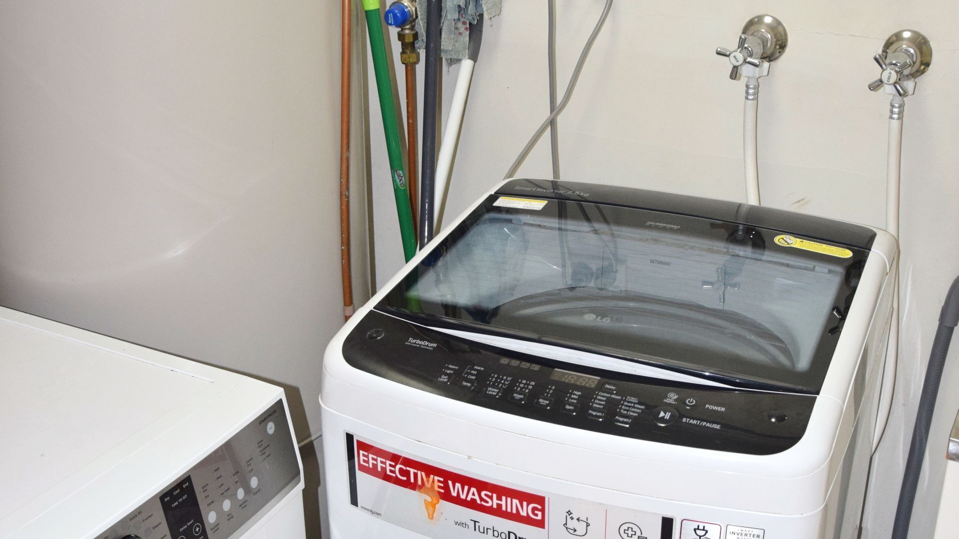 A TurboDrum washing machine with an 'Effective Washing' label, a control panel, and a white wall in the background.