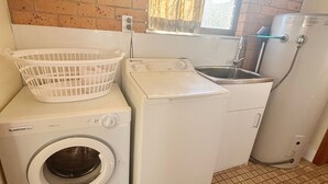 Ein kleiner Waschraum mit einer Waschmaschine mit Frontlader, einem Trockner und einem Spülbecken.