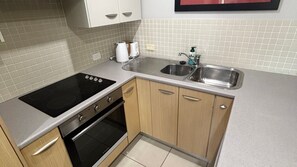 A kitchen with a stove, oven, sink, and cabinets. - Jubilee Apartment 11 (SOUTH WEST ROCKS)