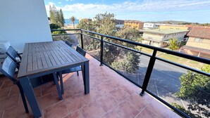 A balcony with a table and chairs, overlooking a residential area and a beach. - Paragon Apartment 7 - walk to the beach (SOUTH WEST ROCKS)