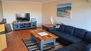 Relax in this stylish living room with a sofa, coffee table, flat-screen TV, and a beautiful beach scene painting.