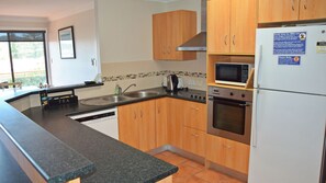 Enjoy cooking in this well-equipped kitchen with a granite countertop, stainless steel appliances, and wooden cabinets.
