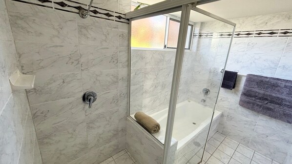 A bathroom with a glass-enclosed shower, a bathtub, and a towel rack. - Ocean Shores Apartment 13 (SOUTH WEST ROCKS)