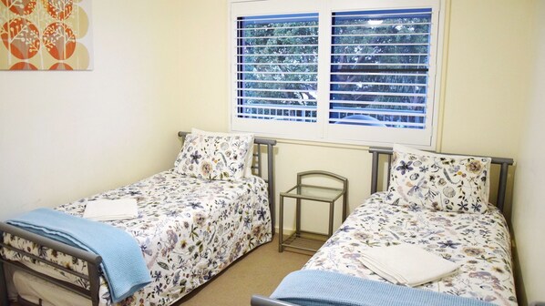 A twin room with two single beds, a window with blinds, and a radiator. - Jubilee Apartment 14 - Linen supplied (South West Rocks)