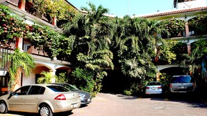 A building with multiple balconies, some with plants and flowers. There are cars parked in front. - Hotel Posada Del Sol (Apatzingan)