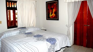 A bedroom with a bed, a window with curtains, a framed picture on the wall, and a red door. - Hotel Posada Del Sol (Apatzingan)