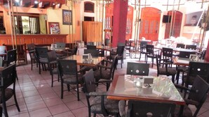 A restaurant with multiple tables and chairs, tiled flooring, and wooden decor. - Hotel Posada Del Sol (Apatzingan)