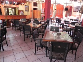A restaurant with multiple tables and chairs, tiled flooring, and wooden decor.