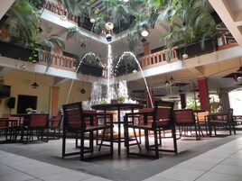 A spacious indoor area with a central fountain, multiple levels with balconies, and numerous seating arrangements.