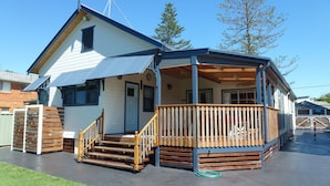 A two-story house with a covered porch and a wooden staircase leading to the entrance.