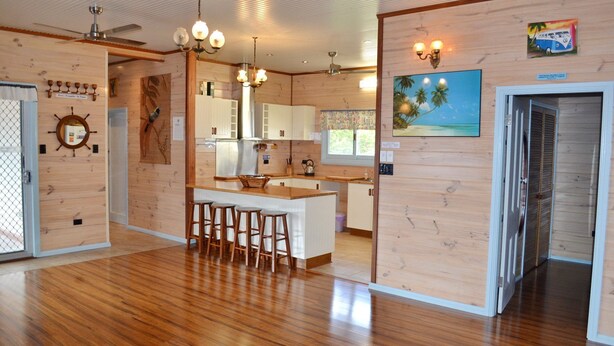 A spacious kitchen with wooden cabinets, a central island with stools, and a dining area.