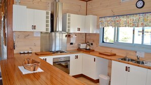 A kitchen with wooden cabinets, a stainless steel range hood, a toaster, and a window with a floral curtain.