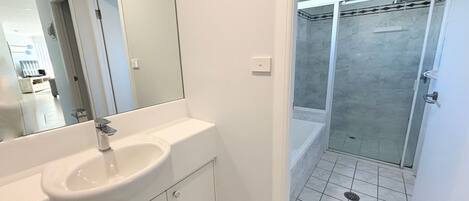 A bathroom with a white sink, mirror, and shower area.