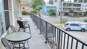 A balcony with outdoor seating, a view of the street, and a building labeled "Dunbar Court" in the background. - Wards Holiday Flat 7 (SOUTH WEST ROCKS)