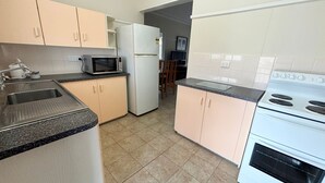 A kitchen with a sink, microwave, refrigerator, and stove. - Clarkes Flat 4 - walk to the beach (South West Rocks)