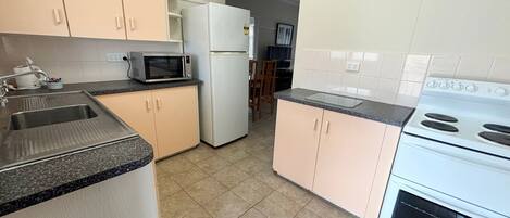 A kitchen with a sink, microwave, refrigerator, and stove.