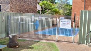 A fenced pool area with a sign indicating it is for tenants only and under video surveillance.