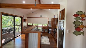Een moderne keuken met houten kastjes, een centraal eiland en uitzicht naar buiten.