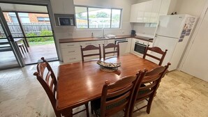 A kitchen with a dining table, chairs, a microwave, oven, and a refrigerator. - Three/Fifty Four Straight St Hat Head - Bring your own linen (Hat Head)