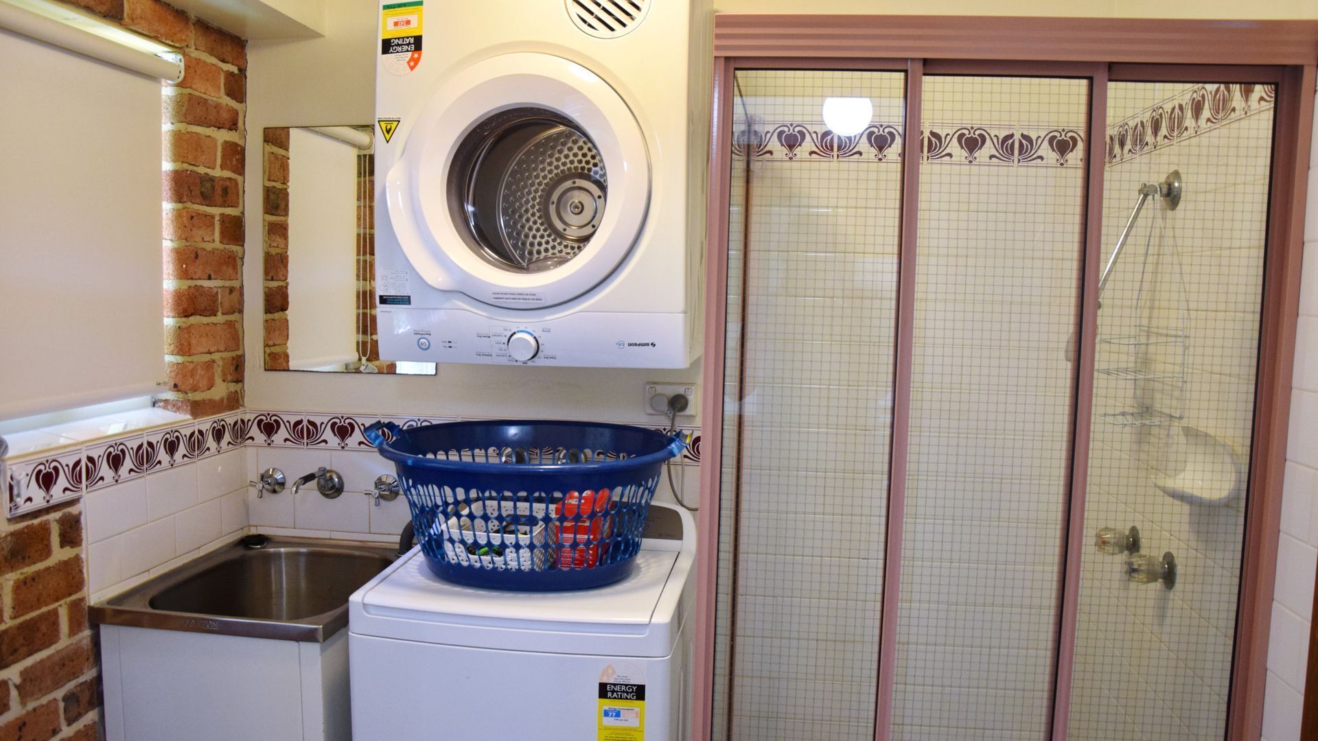 A laundry room with a washing machine, a dryer, and a blue basket filled with clothes.