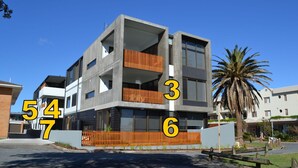A modern multi-story residential building with balconies, a gated entrance, and a palm tree in the background. - Waterford Apartment 7 (SOUTH WEST ROCKS)