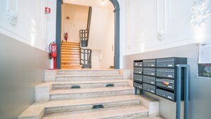 A staircase with a fire extinguisher on the wall, a metal railing, and a filing cabinet with drawers. - Estrela Neoclassical Apt River View (Lisbon)
