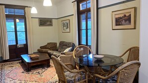 Een gezellige woonkamer met een bank, stoelen, een glazen tafel en een kamerkleed met dessin.