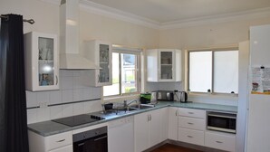 Una cucina moderna con mobili bianchi, forno integrato, microonde e una finestra che offre luce naturale.