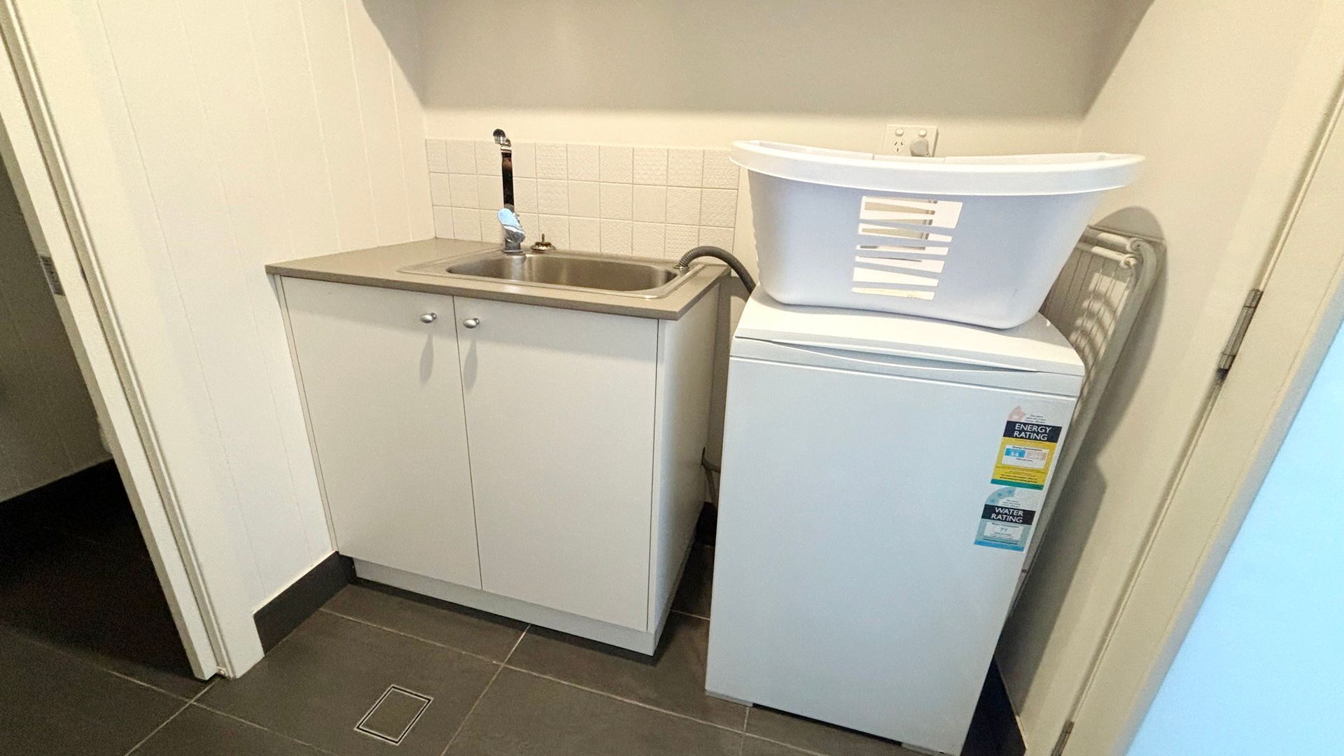 A compact kitchenette with a sink, a small refrigerator, and a trash bin.