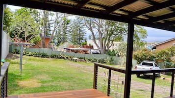 Relax in a sheltered outdoor space with a deck overlooking a well-maintained lawn and trees.