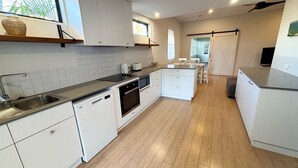 Una cucina moderna con mobili bianchi, un lavello in acciaio inossidabile e un pavimento in legno.