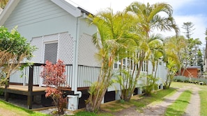 Surrounded by lush tropical plants, this single-story building features a lattice window design and a wooden deck.