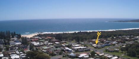 A coastal residential area with houses, a beach, and a clear view of the ocean.