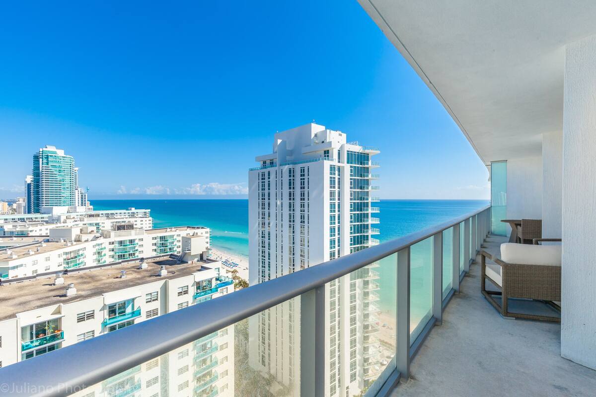 Ein Balkon mit Blick auf das Meer und hohe Gebäude.
