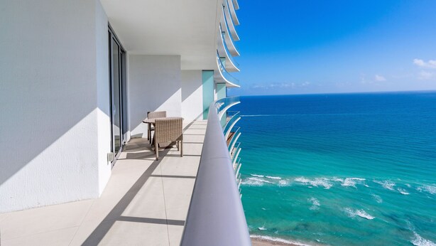 A balcony with a view of the ocean, a chair, and a table. - Private Ocean Condos - Hyde Beach Resort (Hollywood)
