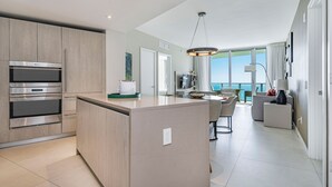 A modern kitchen with built-in appliances and a large island, leading to a dining area with a view of the ocean. - Private Ocean Condos - Hyde Beach Resort (Hollywood)